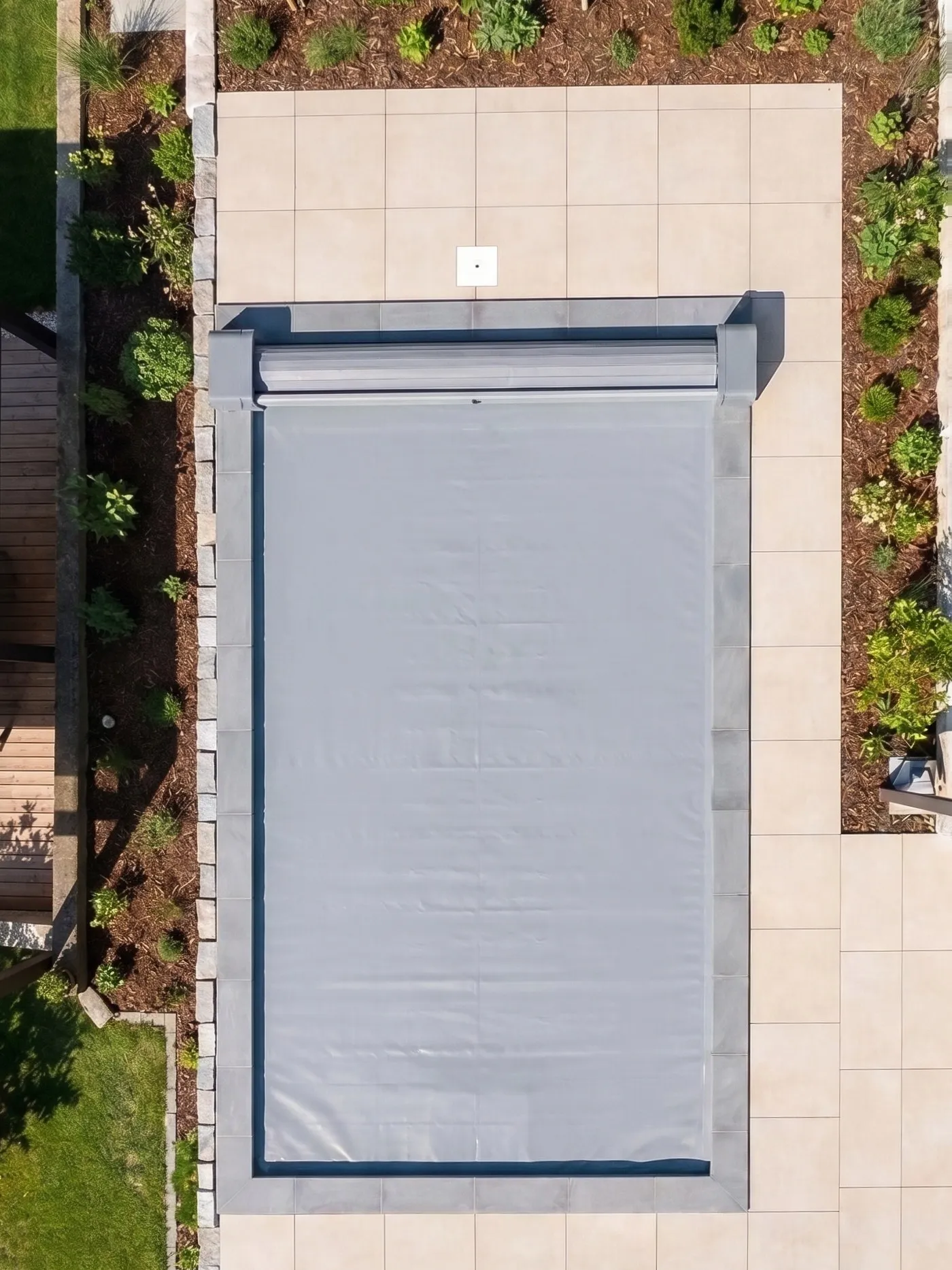 Piscina interrata vista dall’alto con la copertura a tapparella stesa sull’acqua