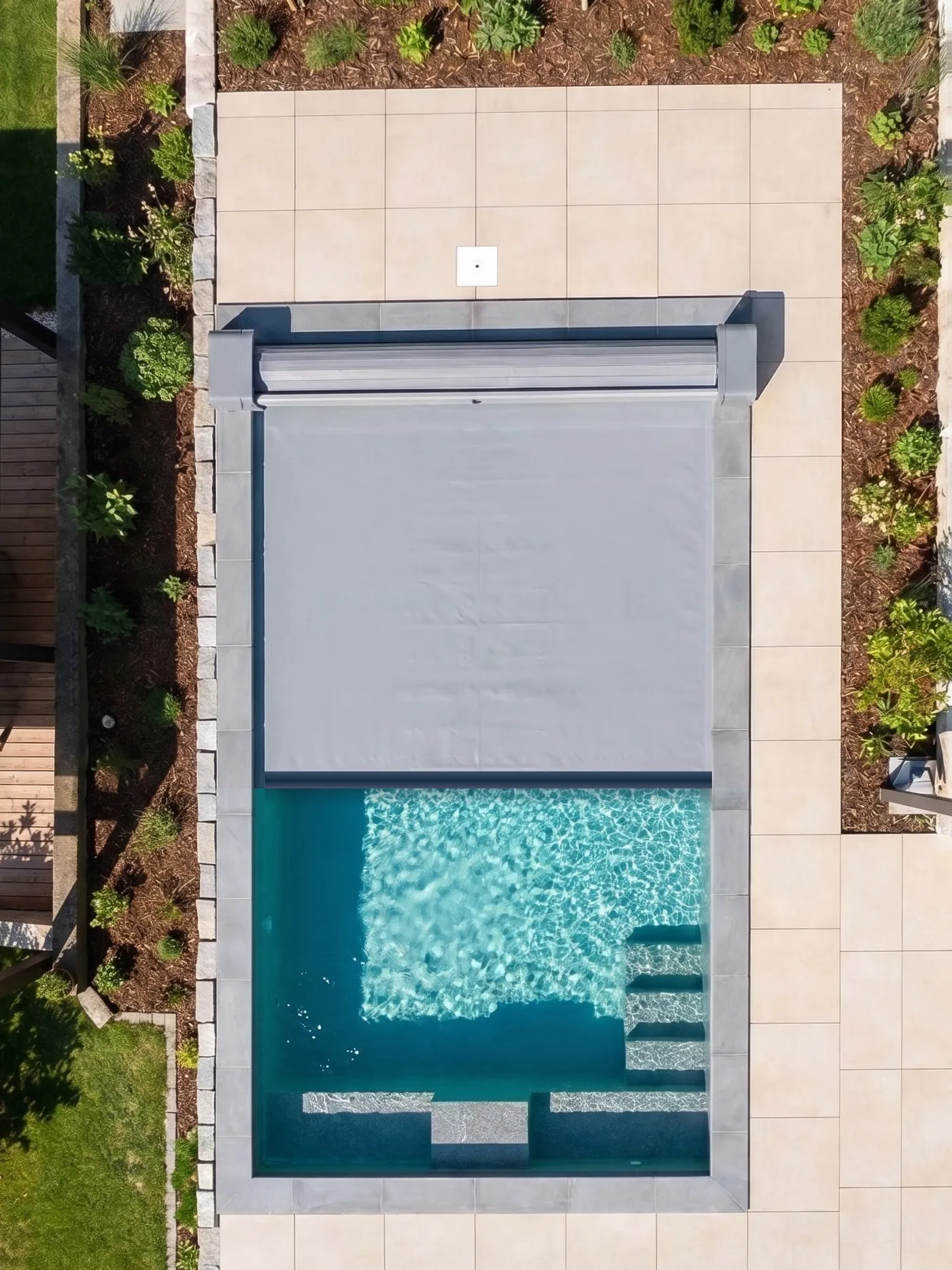 Piscina vista dall’alto con la copertura a tapparella stesa per metà della vasca