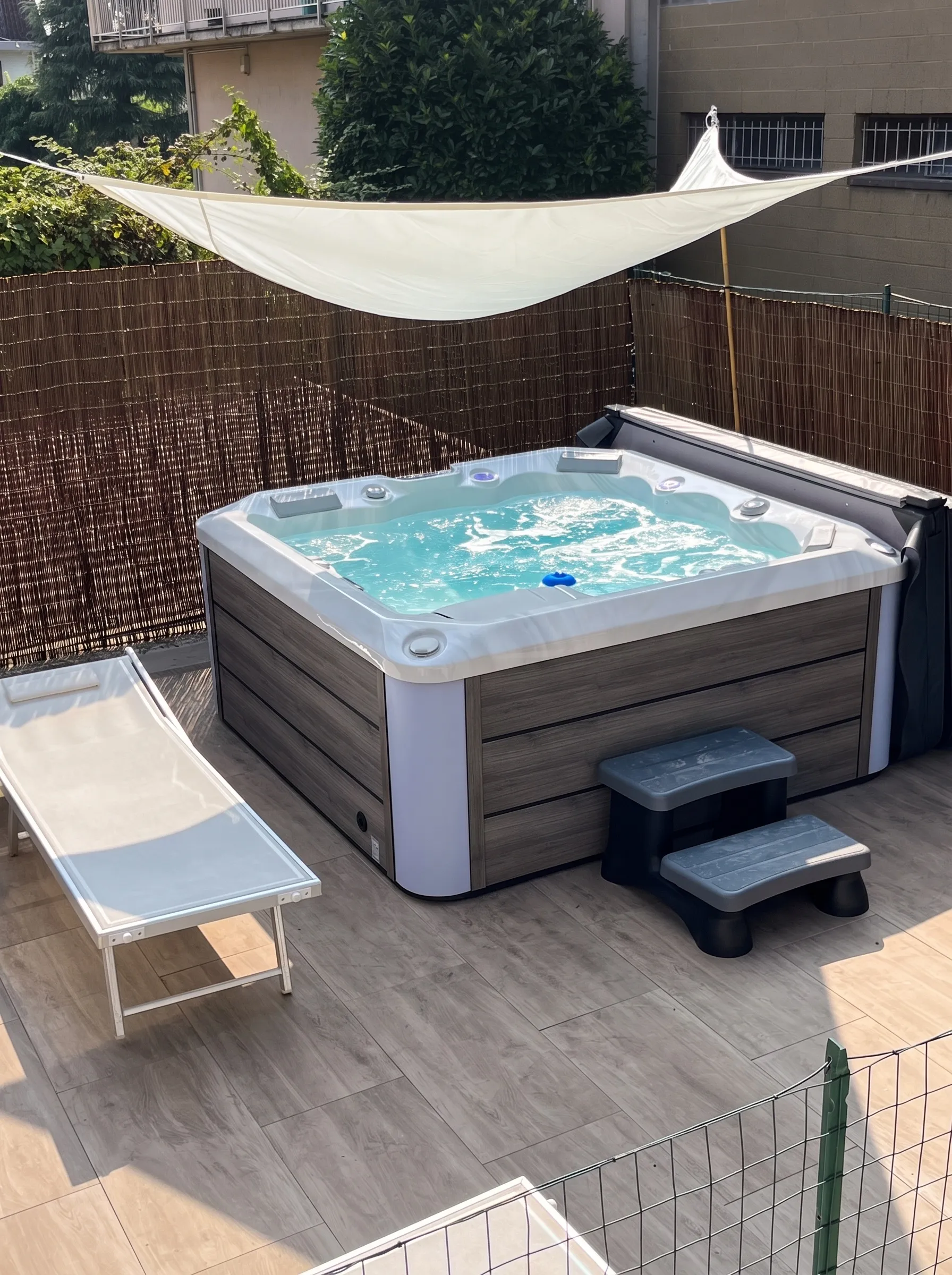 Spa idromassaggio con i getti in funzione su una terrazza, sotto una vela ombreggiante
